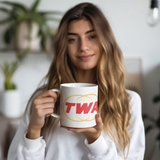TWA_Twin_Globe_Logo_Coffee_Mug_Model_Holding_LH_Mockup.png